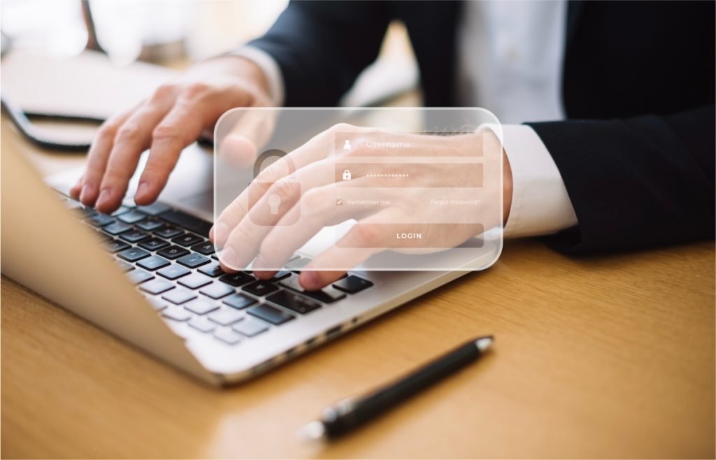 La imagen muestra a una persona escribiendo en un teclado de laptop, con un enfoque en las manos. La persona parece estar ingresando datos en un formulario de inicio de sesión que aparece superpuesto en la imagen, lo que sugiere un contexto de seguridad o acceso a una plataforma digital. La imagen transmite temas de trabajo en oficina, uso de tecnología y ciberseguridad, ideal para ilustrar conceptos relacionados con acceso seguro a sistemas, software empresarial, o procesos de autenticación en línea.